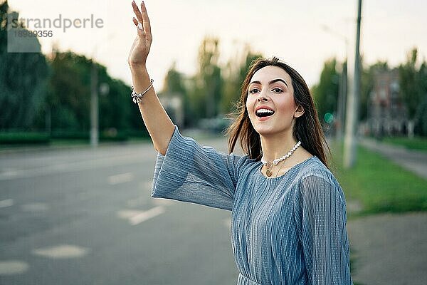 Junge hübsche Frau winkt erhobenen Hand Trampen oder begrüßen Freunde auf Stadt Hintergrund. Hallo  Gruß Konzept