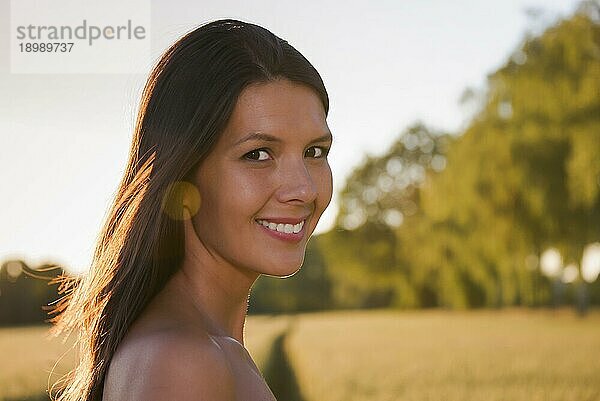 Schöne junge Frau in einem Weizenfeld stehend  lächelnd