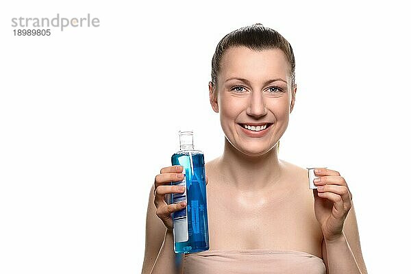 Close up Lächelnde junge Frau hält eine Flasche Mundwasser in einer Kappe  während sie in die Kamera schaut  vor weißem Hintergrund
