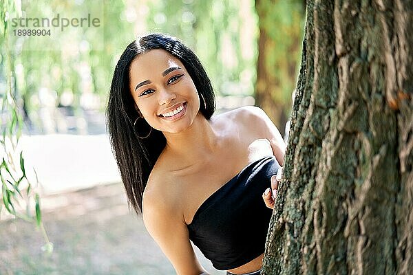 Hübsche lächelnde afroamerikanische Frau posiert im Park. Entspannen  Freizeit  weibliche Schönheit Konzept