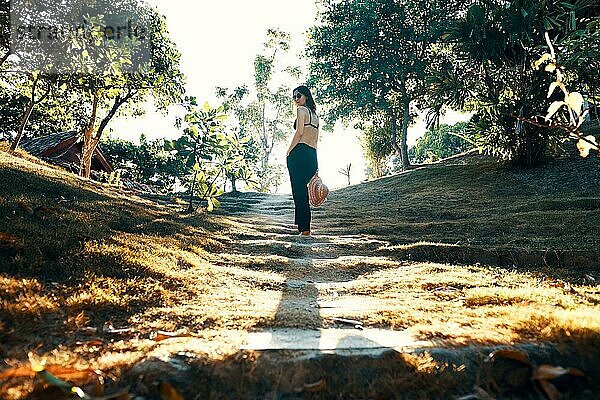 Junge schöne Frau posiert im grünen tropischen Park im Sonnenlicht. Erfolg  Ziel Konzept