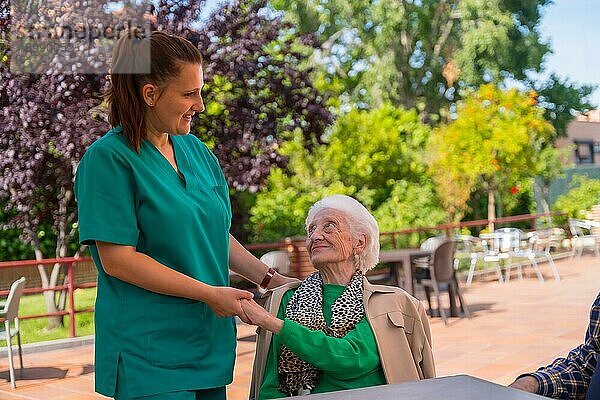 Eine ältere oder reife Frau mit einer Krankenschwester im Garten eines Pflegeheims in einem Moment der Zuneigung