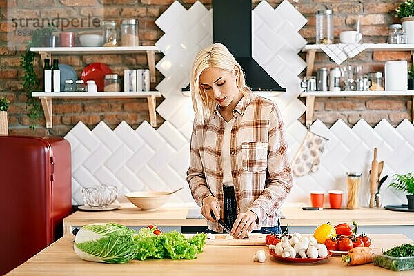 Lächelnde junge Frau kocht gesundes Essen in der Küche zu Hause. Vegane Diät Lebensmittel Konzept