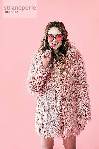 Mode Porträt der hübschen Glamourfrau mit Lutscher Blick zur Kamera über rosa Hintergrund