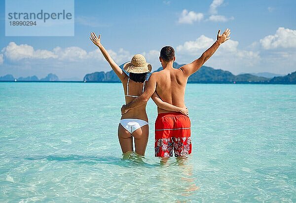 Rückansicht eines glücklichen Paares  das seinen paradiesischen Strandurlaub im warmen tropischen Meerwasser genießt. Reiseziel