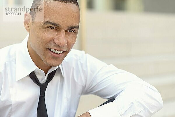Attraktiver lächelnder Geschäftsmann mit gelockerter Krawatte und aufgeknöpftem Kragen  der zur rechten Seite des Bildes blickt  Nahaufnahme von Kopf und Schultern