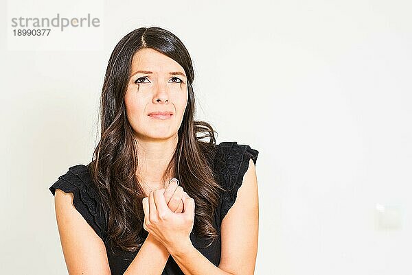 Attraktive junge weinerliche verzweifelte Frau  die ihre Hände mit einem Ring in der Angst vor einem weißen Hintergrund ringt