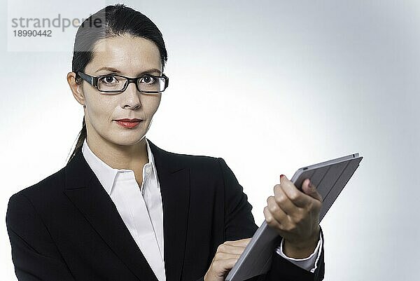 selbstbewusste Business Managerin  die an einem Tabletcomputer arbeitet  während sie mit ernstem  nachdenklichem Gesichtsausdruck in die Kamera schaut  Studioporträt mit Kopierbereich