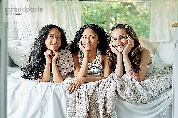 Schöne multiethnische Mädchen haben Spaß zusammen  entspannen und liegen auf dem Bett posiert im Inneren des Wohnmobils. Frauen Freundschaft und Frauen Schönheit Konzept