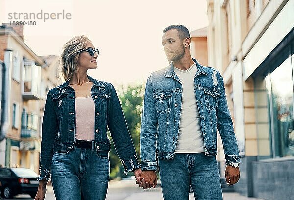 Schönes junges Paar hält sich an den Händen und lächelt beim Spaziergang im Freien. Liebe  Dating Konzept