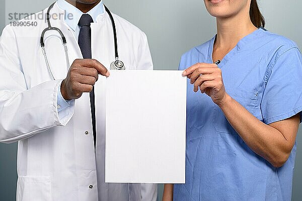 Nahaufnahme des Oberkörpers eines Arztes und einer Krankenschwester  die ein leeres weißes Schild mit Platz für Ihre medizinische Warnung  Ankündigung oder Werbung in einem Gesundheitskonzept hochhalten