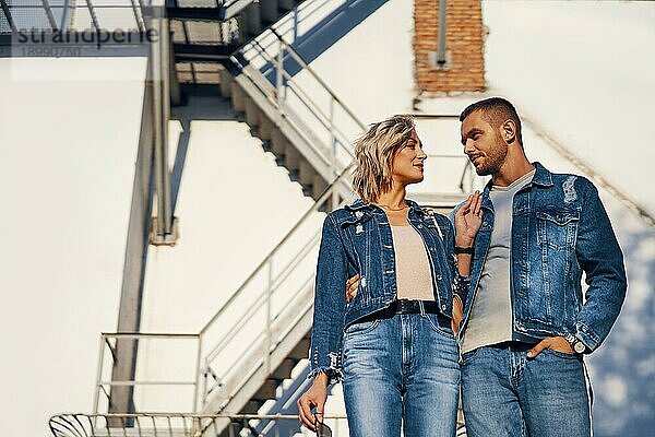 Junge schöne Frau und Mann in Jeans Stoff posiert auf städtischen Architektur. Paar Beziehung  Modekonzept