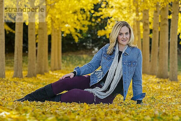 Ein schönes blondes Modell posiert im Freien in einem Feld mit gelben Blättern