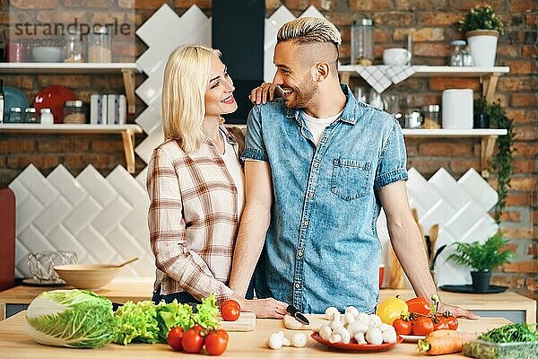 Lächelnd junges Paar Kochen zusammen vegetarische Mahlzeit in der Küche zu Hause. Gesunder Lebensstil Konzept