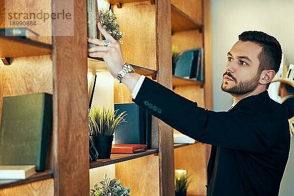 Eleganter Mann nimmt Buch aus Bücherregal. Bildung und Hobby Konzept