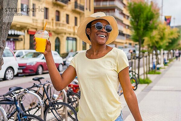 Schwarze ethnische Frau trinkt einen Orangensaft und genießt den Sommer in der Stadt