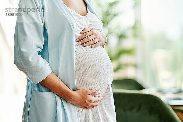 Nahaufnahme einer schwangeren Frau  die ihren Bauch hält. Baby erwartet  Mutterschaft Pflege  Schwangerschaft und Sicherheit Konzept