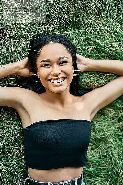 Oben Ansicht Porträt der hübschen glücklichen afroamerikanischen Frau entspannt auf Gras im Park. Rest  weibliche Schönheit Konzept