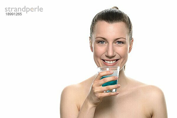 Close up Lächelnde junge Frau hält ein Glas Mundwasser in eine Kappe  während sie in die Kamera schaut  vor weißem Hintergrund