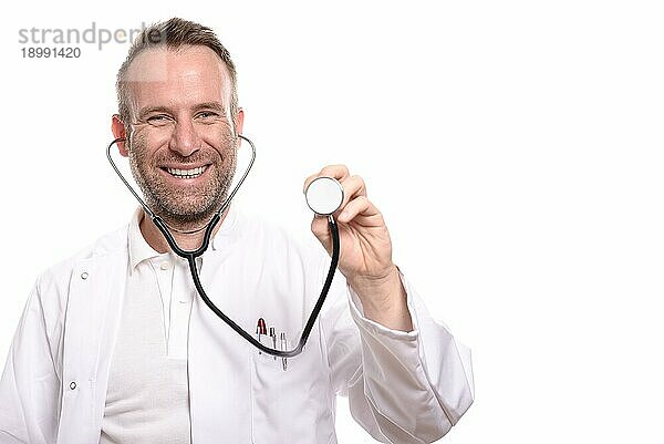 Lächelnder  unrasierter männlicher Arzt  der die Scheibe eines Stethoskops in der Hand hält und bereit ist  eine Untersuchung durchzuführen  während er in die Kamera blickt  vor weißem Hintergrund