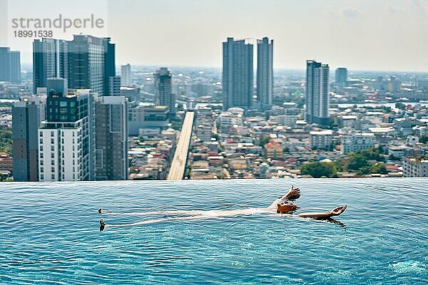 Junge Frau entspannt sich im Schwimmbad auf dem Dach und schwimmt im Wasser. Sommerurlaub Konzept