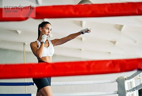 Weibliche Boxerin übt ihre Schläge in einem Boxstudio. Sportliche Frau mit direktem Schlag. Sport Konzept