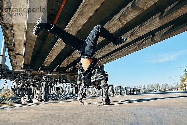 Junger Mann Breakdancer tanzt auf städtischen Hintergrund Durchführung akrobatische Stunts. Straßenkünstler Breakdance im Freien