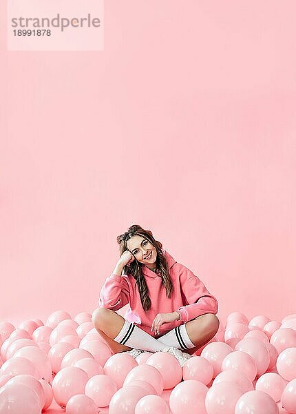 Mode Porträt der jungen charmanten lächelnde Frau posiert mit rosa Luftballons auf rosa Hintergrund. Pop Art. Feiern  festlich  Spaß Konzept. Kopieren Raum