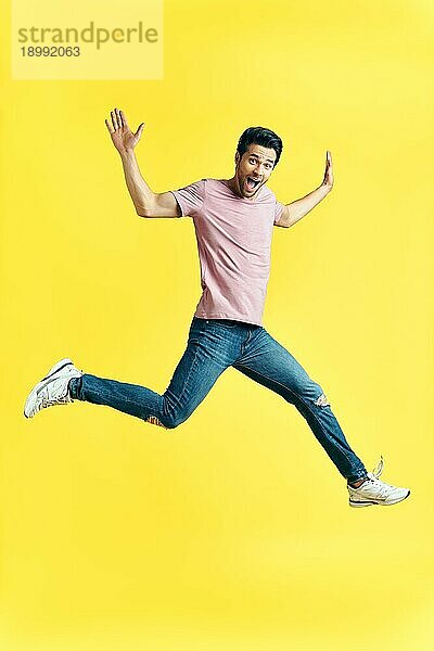 Happy aufgeregt Mann springt auf gelben Hintergrund. sorglos und Spaß Konzept