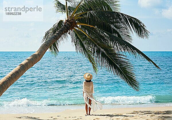 Rückenansicht der hübschen jungen Frau entspannen und genießen Meer stehen unter Palme am tropischen Strand. Sommerurlaub Konzept