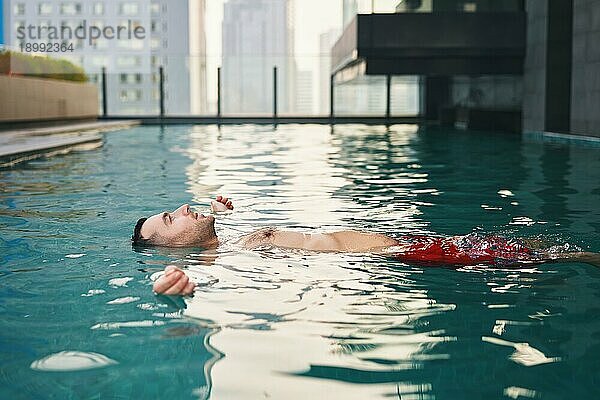 Sorgloser Mann entspannt sich im Schwimmbad. Urlaub  Sommerurlaub Konzept