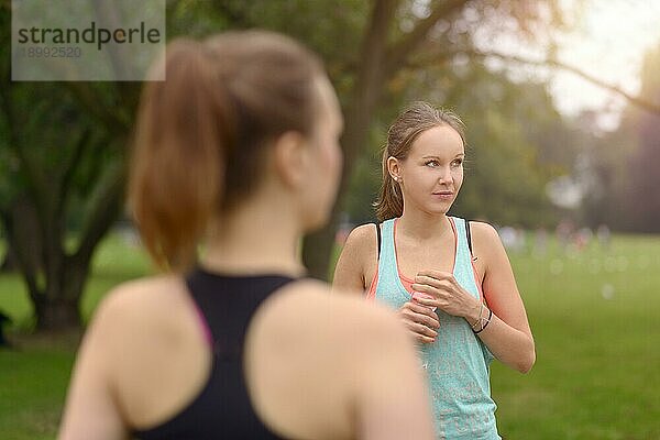 Sportliche Frauen trinken Wasser  während sie sich nach einem Outdoor Training im Park ausruhen