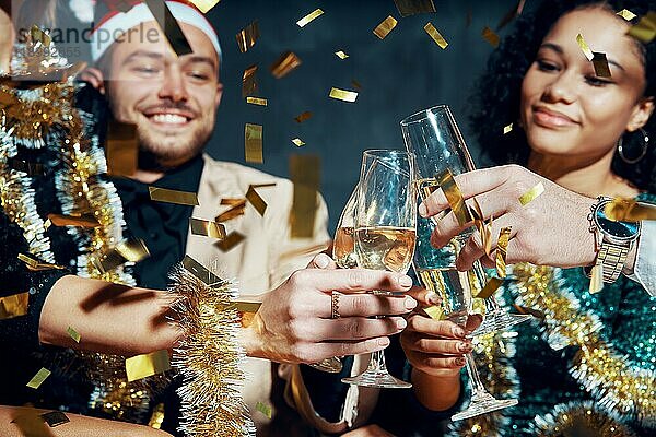 Multiethnische Freunde stoßen mit Champagner an  feiern Weihnachten oder Neujahr  gratulieren sich gegenseitig und genießen die Party. Feiern und Prost Konzept  Urlaub Hintergrund