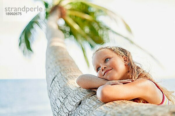 Glücklich träumen schönes Kind entspannen am tropischen Strand mit Palme. Sorglos Konzept