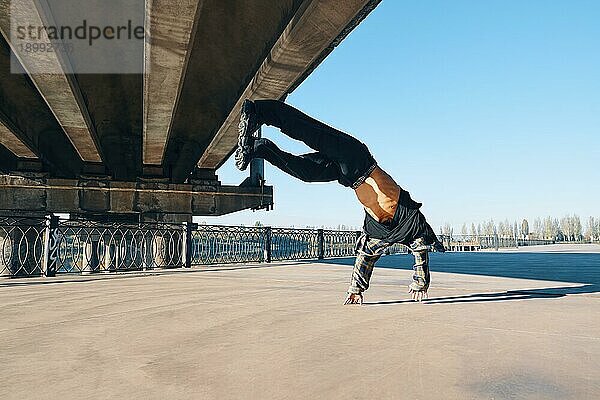 Junger Mann Breakdancer macht Salto akrobatische Stunts tanzen auf städtischen Hintergrund. Straßenkünstler Breakdance im Freien