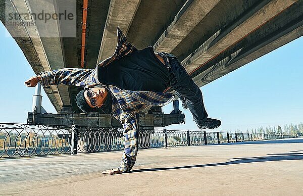 Junger Mann Breakdancer tanzt auf städtischen Hintergrund Durchführung akrobatische Stunts. Straßenkünstler Breakdance im Freien