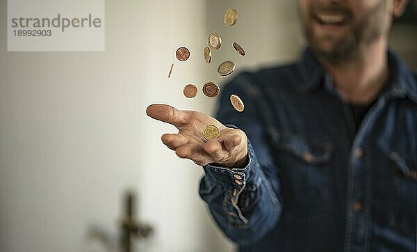 Fröhlicher Mann wirft Geldmünzen in die Luft