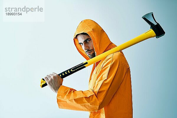 Junger gruseliger Mann in orangefarbenem Regenmantel mit großer Axt auf weißem Hintergrund