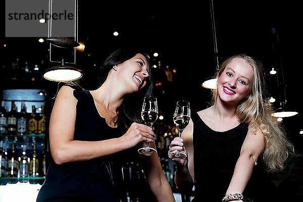 Zwei schöne junge Frauen teilen ihre Freundschaft und feiern mit Champagner in einem schicken Nachtclub
