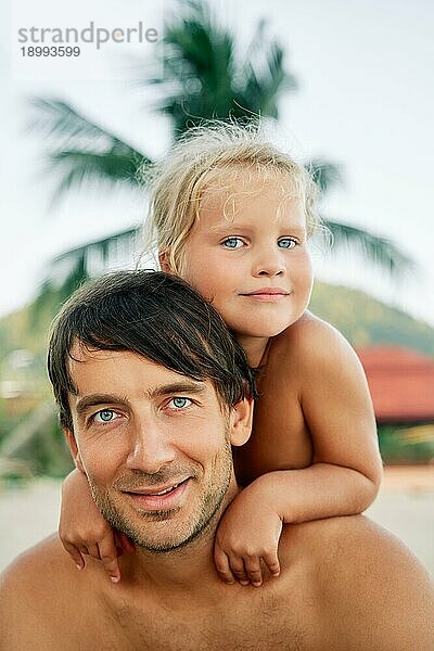 Hübsches kleines Mädchen umarmt ihren Vater am tropischen Strand im Sommerurlaub. Vater und Tochter  Familienkonzept