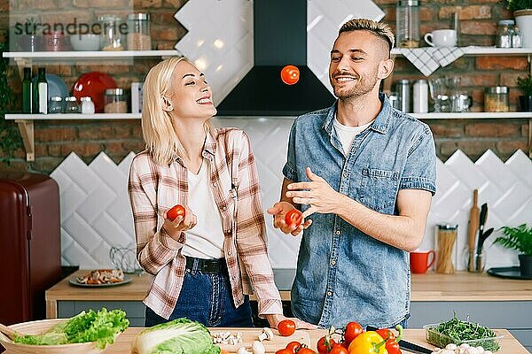 Glückliches lächelndes Paar hat Spaß beim gemeinsamen Kochen in der Küche zu Hause