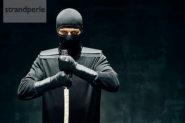 Kämpfende Ninja posiert mit einem Schwert über schwarzem Hintergrund. japanischen Kämpfer Konzept