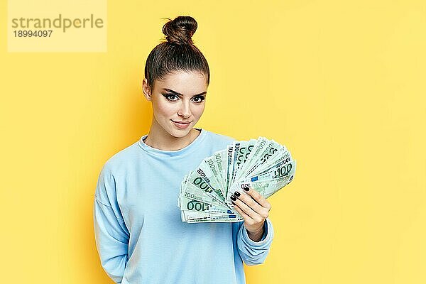 Junge hübsche Frau hält Geldscheine auf gelbem Hintergrund. Motivation  Erfolg Konzept