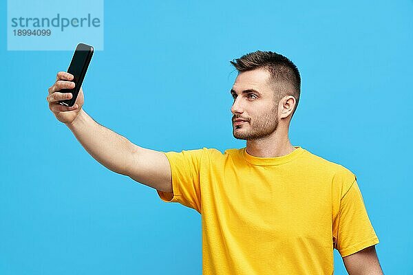 Hübscher junger Mann nimmt Selfie über blaün Hintergrund. Menschen Konzept