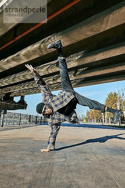 Junger Mann Breakdancer tanzt auf städtischen Hintergrund Durchführung akrobatische Stunts. Straßenkünstler Breakdance im Freien