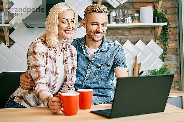 Glückliches Paar trinken Kaffee und mit Laptop entspannen zusammen in ihrer Küche zu Hause