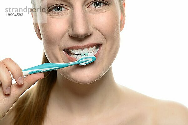 Attraktive nackte Frau putzt sich die Zähne mit einer Zahnbürste in einem medizinischen  zahnärztlichen und Mundhygiene Konzept  Kopf und Schultern vor weißem Hintergrund