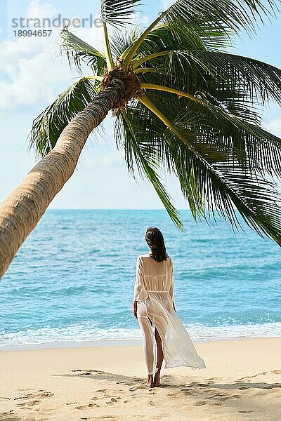 Rückenansicht der hübschen jungen Frau entspannen und genießen Meer stehen unter Palme am tropischen Strand. Sommerurlaub Konzept