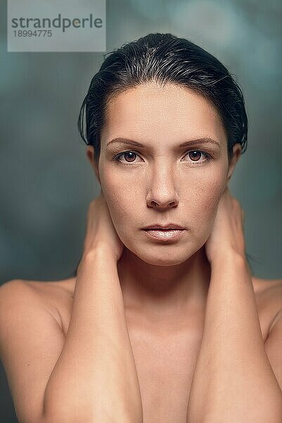 Close Up Porträt der ernsten Frau mit minimalen Make up mit den Händen hinter dem Hals im Studio