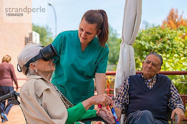 Eine ältere Frau mit der Krankenschwester Blick durch Virtual Reality Brille in den Garten eines Pflegeheims  vr Brille mit dem lächelnden